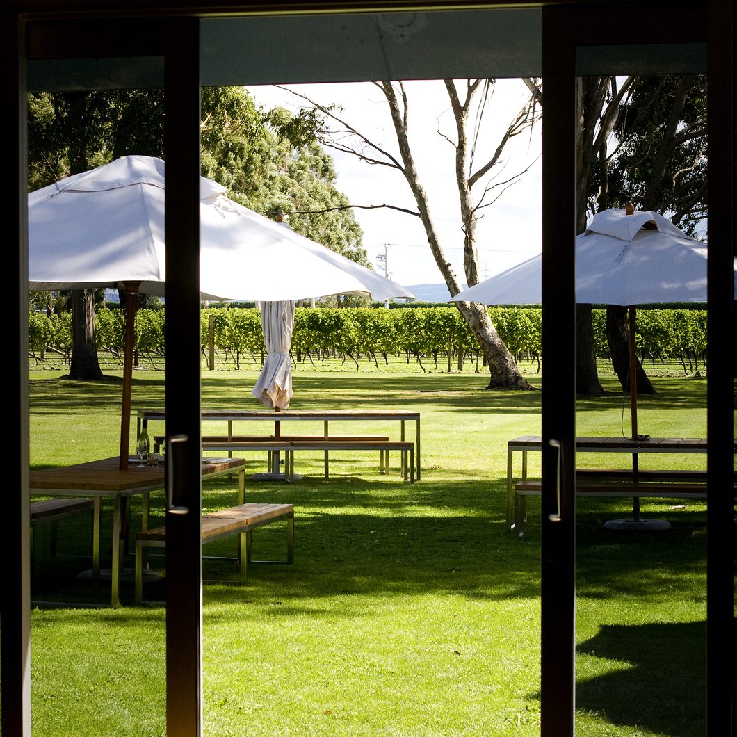 Picnic tables seen through sliding doors in sunny vineyard